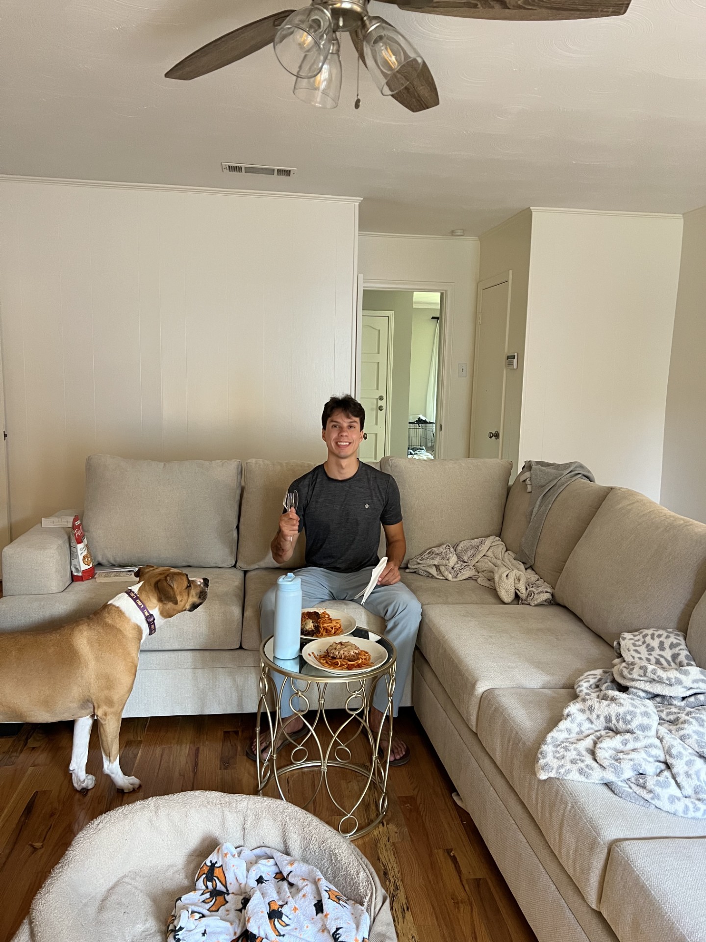 Matthew enjoying their first meal in their new house with Doobie, using a side table as their dining surface